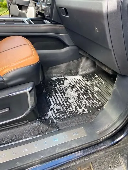 Truck floor mat and door sill covered in cleaning suds